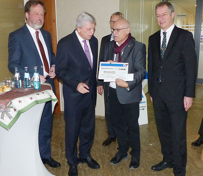 Scheckübergabe (v.l.): Dekan Dr. Lückhoff, Ministerpräsident Bouffier, Diakoniepfarrer Laukel und Dekan Hammann. Im Hintergrund ist Diakonie-Hessen-Vorstand Dr. Clausen zu sehen. (Foto: Diakonie)