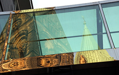 Kirchenturm und -schiff im Spiegel großer Fenster. Kirchenturm und -schiff im Spiegel großer Fenster. Foto: Peter Weidemann, pfarrbriefservice.de