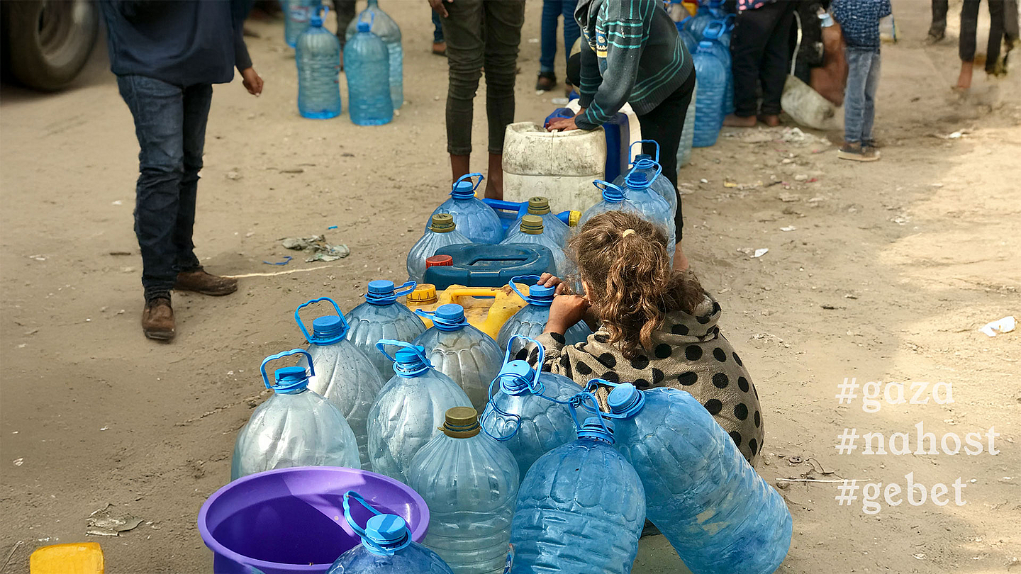 Ein Mädchen hockt zwischen leeren Kanistern in einer Schlange von Menschen, die auf frisches Trinkwasser warten. 