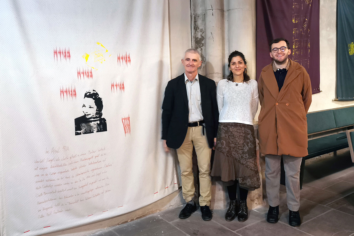 Pfarrer Ulrich Biskamp (links) und die beiden Ausstellungsmacher Maryam Abdolahi (Mitte) und Samuel Linn (rechts) vor einem Exponat der Ausstellung «Ein jüdisches Jahrhundertleben» zum Wirken von Margot Friedländer. 
