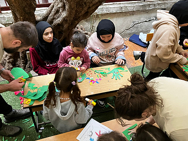 Fünfzehn Studierende sowie mehrere Mitarbeitende und Lehrende der NEST bieten ein- bis zweimal pro Woche Bildungs- und Freizeitprogramme für die geflüchteten Kinder und Jugendlichen an – darunter Bastelangebote und Bewegungsspiele. Das Bild zeigt Kinder beim basteln.