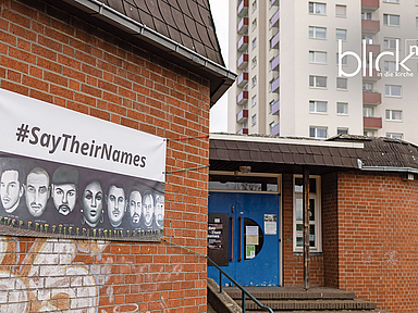 Am Eingang hängt ein Plakat an die Opfer der Hanauer Anschläge. Mit dem Hashtag #SayTheirNames (Sagt ihre Namen) soll die Erinnerung an die Ermordeten wachgehalten werden. 