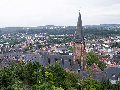 Außenaufnahme der Lutherischen Pfarrkirche in Marburg. Im Hintergrund ist die Stadt Marburg zu sehen.