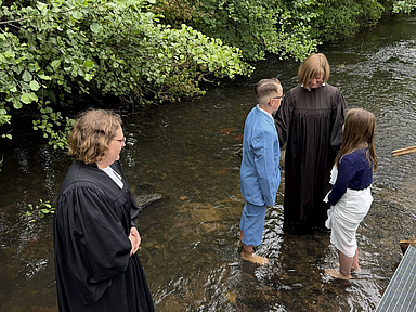 Pfarrerin Doreen Göbel (l.) und Pfarrerin Gudrun Ostheim mit zwei Täuflingen in der Efze