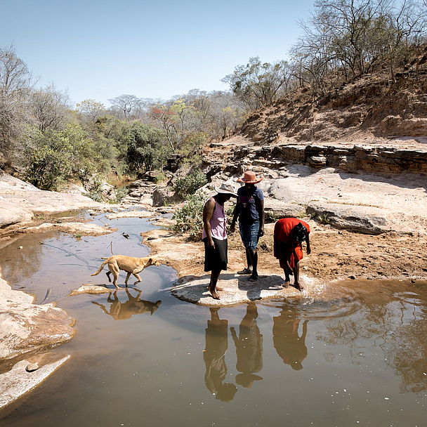 Die Freundinnen Beauty Nyathi (45), Gracious Mujuma (42) und Sihle Hahlani (31) am Fluss Chiurayi. Hier haben sie früher Wasser geholt. Durch MeDRAs Arbeit (BfdW-Partnerorganisation) hat sich ihr Leben sehr verbessert. Sie lernen und unterstützen sich gegenseitig.