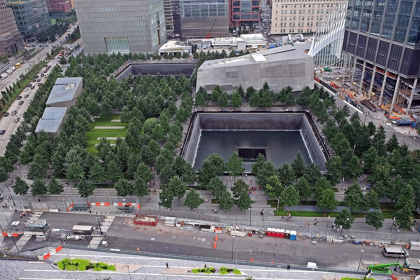 Unser Foto zeigt das 9/11-Memorial, dessen Zentrum das Mahnmal Reflecting Absence (deutsch: Spiegelung des Nichtvorhandenseins) bildet. Besucherinnen und Besucher können dort in zwei große rechteckige Hohlräume blicken, die an die Fundamente der zerstörten Zwillingstürme erinnern.