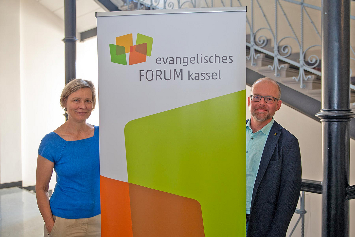 Susanne Jakubczyk und Dr. Rüdiger Jungbluth mit dem frischen Logo, auf dem sich vier transparente Wände erkennen lassen, in deren Mitte ein neuer Raum eröffnet wird.