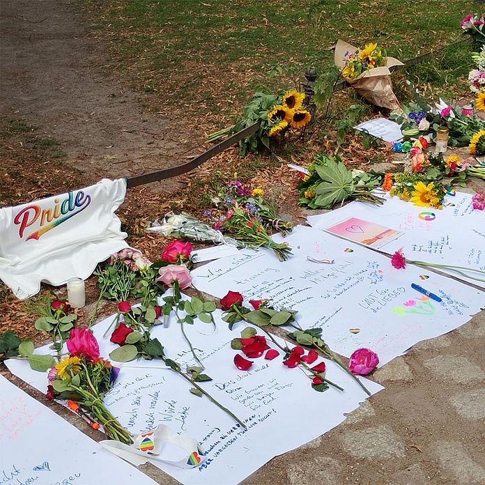 Ein improvisiertes Kondolenzbuch aus großen weißen Papierblöcken liegt auf dem Boden. „Laut für die Liebe“ steht dort und: „Das darf nicht sein.“
