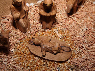 Unser Foto zeigt eine aus Holz geschnitzte Darstellung des Jesuskindes in einer Krippe. 