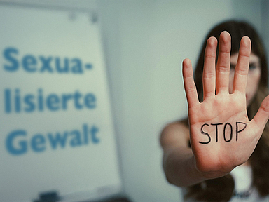 Eine Frau zeigt ihre Hand, auf der Stop geschrieben ist. Daneben steht der Schriftzug "Sexualisierte Gewalt".