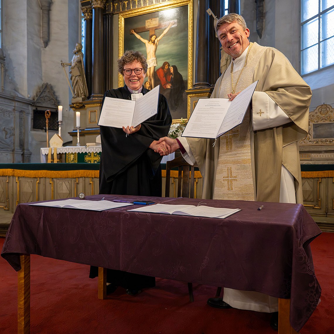 Bischöfin Dr. Beate Hofmann und Erzbischof Urmas Viilma mit der unterzeichneten Partnerschaftsvereinbarung im Tallinner Dom.