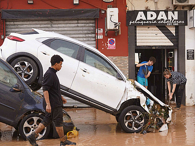 Zwei Autos stehen ineinander gekeilt durch ein Hochwasser 2024 auf einer Straße in Valencia in Spanien 