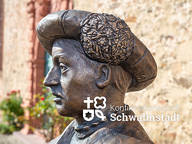 Statue von Landgraf Philipp I. von Hessen mit kunstvollem Hut, Teil einer Figurengruppe auf dem Paradeplatz in Ziegenhain, vor einer alten Sandsteinmauer. Die Skulptur erinnert an die Einführung der Konfirmation. Zu sehen ist eine Statue von Landgraf Philipp I. von Hessen mit einem reich verzierten Hut. Die Figur steht auf dem Paradeplatz in Ziegenhain vor einer alten Sandsteinmauer und erinnert an die Einführung der Konfirmation durch Philipp und Martin Bucer.