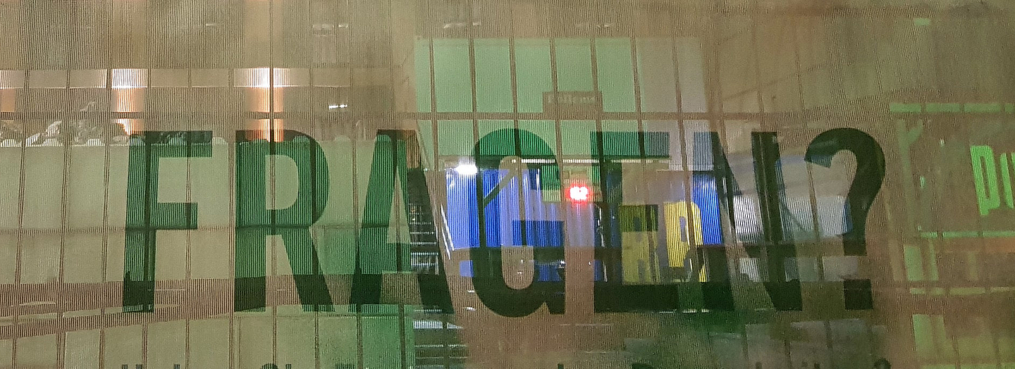 Das Wort "Fragen?" auf eine Art von Bauzaun in einem großen Gebäude.