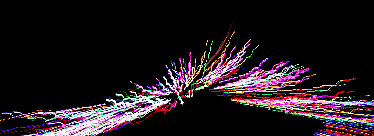 Bunte, leuchtende Linien verlaufen symmetrisch auf schwarzem Hintergrund.