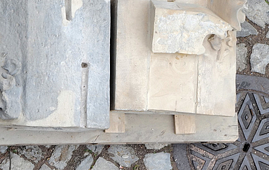 Verschiedenartige Bausteine eines Kirchengebäudes liegen aufbereitet zum Verbauen auf Holzpaletten auf einer gepflasterten Fläche. Foto (Ausschnitt): Peter Weidemann, pfarrbriefservie.de