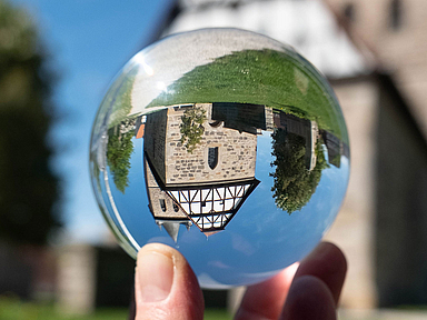 Kirchengebäude neu gedacht: Mit der Initiative sollen im Dialog Ideen entstehen, Kirchenräume über den gottesdienstlichen Bereich hinaus zu nutzen und als Orte für Begegnung, Kultur und Gemeinschaft zu öffnen. Unser Foto zeigt die Evangelische Kirche in Großenritte durch eine Glaskugel betrachtet. Die Kirche stammt aus dem 16. Jahrhundert. 