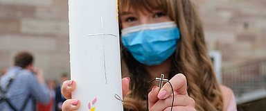 Unser Foto zeigt eine Konfirmandin der Markuskirchengemeinde in Kassel mit Mund-Nasen-Schutz, Konfirmationskerze und Kreuz. (Foto: medio.tv/Schauderna) 
