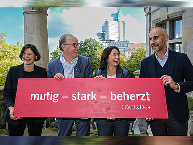 Generalsekretärin Kristin Jahn, Landesbischof Ralf Meister, Präsidentin Anja Siegesmund und Oberbürgermeister Belit Onay halten eine Tafel mit dem Kirchentagsmotto