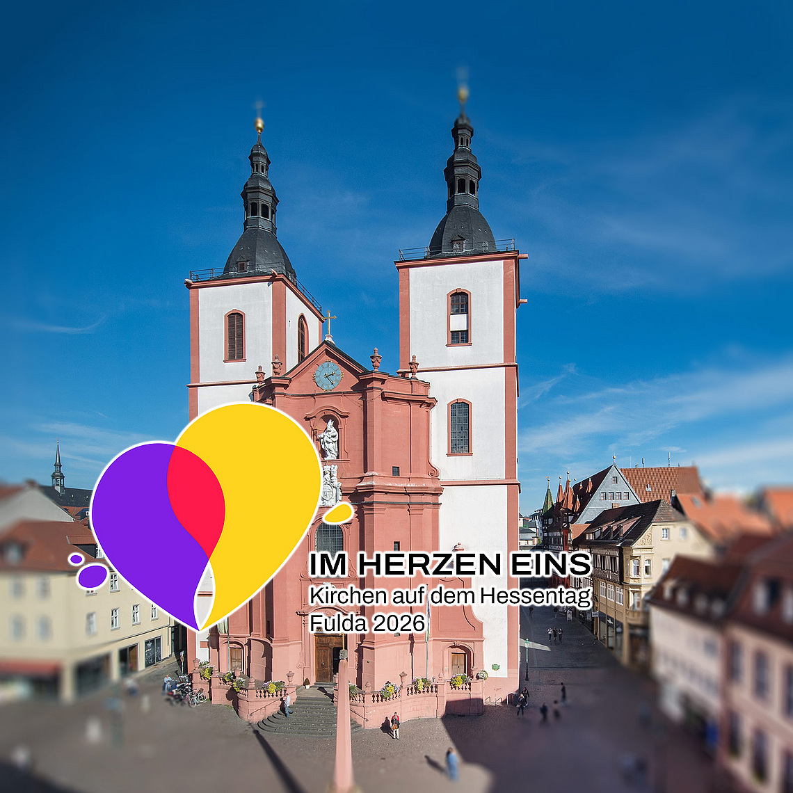 «Im Herzen eins»: Das Hessentagsmotto kommt auch in einem gemeinsamen Logo zum Ausdruck – ein Symbol des Miteinanders. Im Hintergrund ist die Fuldaer Stadtpfarrkirche zu sehen, die während des Hessentags zur multimedial inszenierten Hessentagskirche wird.