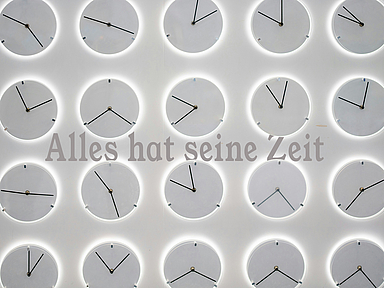Unser Foto Zeigt eine Wand voller Uhren mit der Aufschrift "Alles hat seine Zeit"