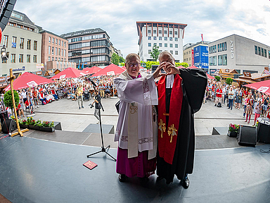 Abschlussgottesdienst in Fulda: Stadtpfarrer Stefan Buß (l., Bistum Fulda) und Dekan Dr. Thorsten Waap (r., Ev. Kirchenkreis Fulda) bilden ein Herz, frei nach dem Motto der Kirchen auf dem Hessentag 2026: "Im Herzen eins".