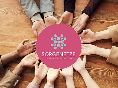 Hände halten ein Schild mit der Aufschrift "Sorgenetze - Gelebte Nächstenliebe"