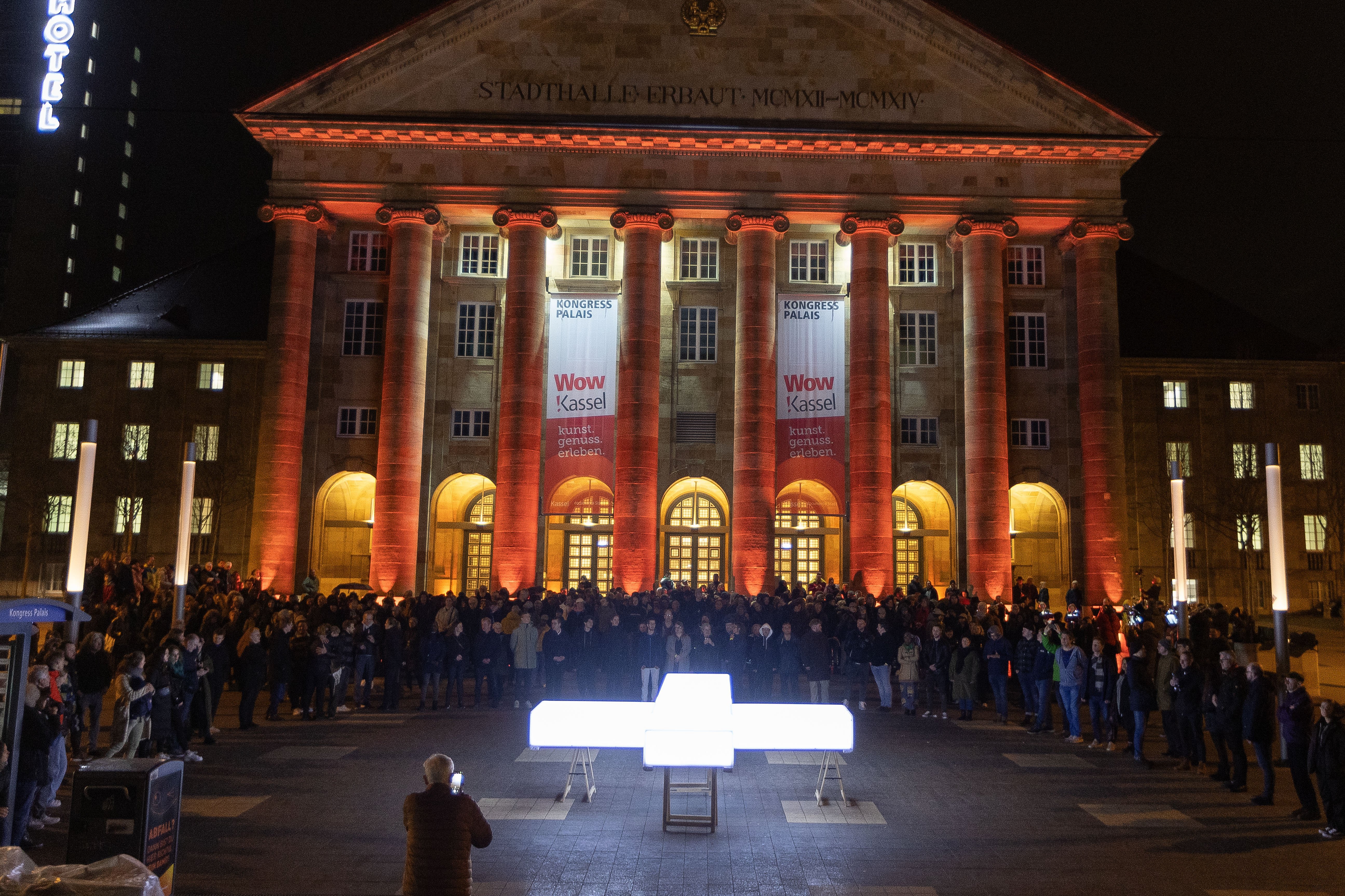 Leuchtkreuz und Prozessionsteilnehmer vor der Stadthalle in Kassel. 