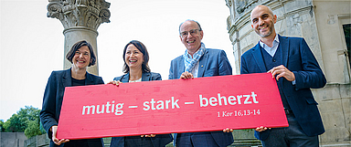 Generalsekretärin Kristin Jahn, Landesbischof der Evangelisch-lutherischen Landeskirche Hannovers Ralf Meister, Kirchentagspräsidentin Anja Siegesmund und Oberbürgermeister der Landeshauptstadt Hannover Belit Onay mit dem Motto des Kirchentags 2025 (Foto: Kirchentag/Jens Schulze)