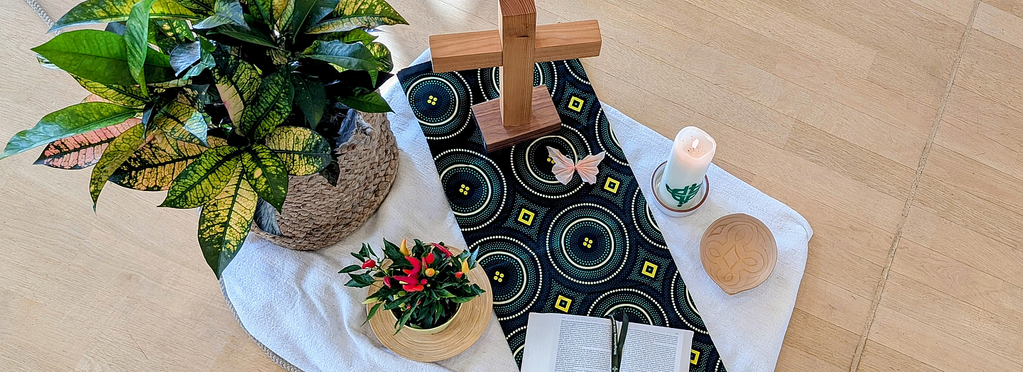 Mitte zum Weltgebetstag 2026: Bibel, WGT-Kerze, Batikstoff aus Nigeria, Pflanze, Peperoni-Pflanze, Kalebasse
