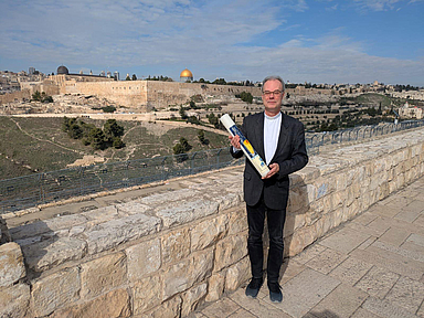 Dr. Andreas Goetze zeigt sich mit einer ökumenische Wanderfriedenskerze in Jerusalem.