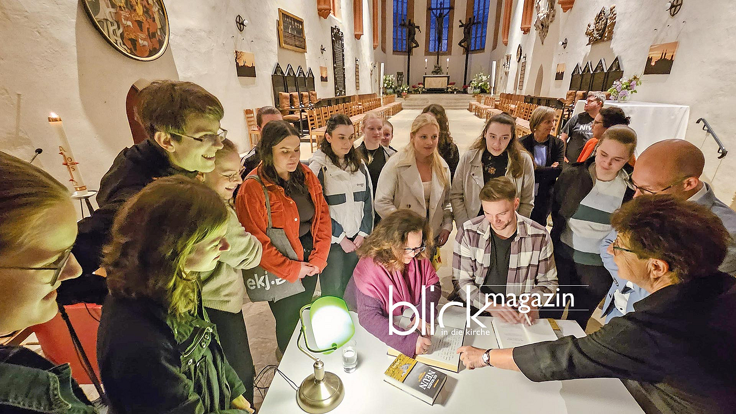 Autorin Gwen Strauss und Diakon Fabian Hanspach tragen sich in das Goldene Buch der Stadt ein. Im Wurzener Dom: Autorin Gwen Strauss und Diakon Fabian Hanspach tragen sich in das Goldene Buch der Stadt ein. Rund um den Tisch stehen das Übersetzungsteam der Evangelischen Jugend Wurzen sowie Oberbürgermeister Marcel Buchta (blaues Hemd)