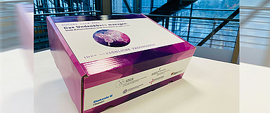 Teilnehmende am Social Talk erhalten für die Tagung eine interaktive Box, die zum Start der Online-Veranstaltung gemeinsam vor dem Bildschirm ausgepackt werden kann. (Foto: IZGS/Social Talk)