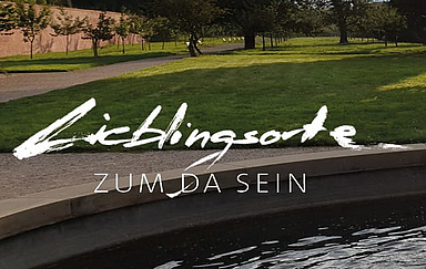 Blick in einen Park mit Brunnen. "Lieblingsorte zum da sein" ist mit weißer Handschrift in das Foto geschrieben. Foto und Handschrift: Birgitta Schwansee