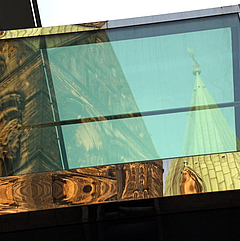 Kirchenturm und -schiff im Spiegel großer Fenster. 