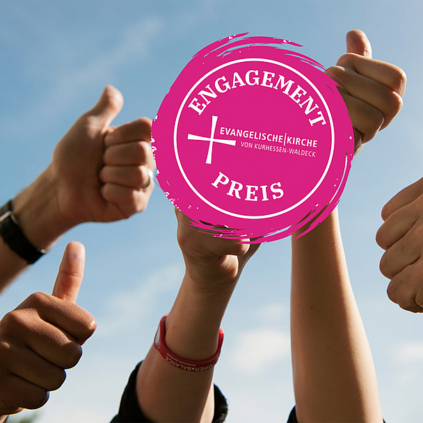 Unser Foto zeigt Hände mit der Daumen-hoch-Geste und das Logo des Preises 