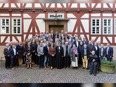 Eine größere Gruppe von Menschen steht vor einem Fachwerkgebäude in Bad Hersfeld. In der vorderen Reihe in der Mitte steht Bischöfin Dr. Beate Hofmann. Links neben ihr steht Pfarrerin Bettina von Haughwitz, die Vorsitzende des Pfarrvereins. Es handelt sich um die Jubilarinnen und Jubilare der Ordinationsjahrgänge, die gemeinsam für ein Gruppenfoto posieren.