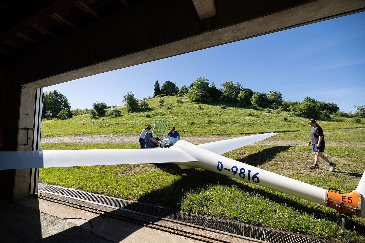 Die Segelflugzeuge müssen aus der Halle geschoben werden, bevor sie zur Startbahn gebracht werden
