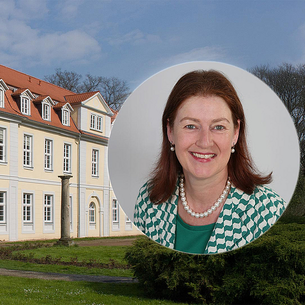 Das Foto zeigt das historische Gebäude „Friedrichsbad“ im Park des Gesundbrunnens in Hofgeismar. Die gelbe Fassade mit rotem Dach und mehreren Fensterreihen ist von einer grünen Rasenfläche umgeben. Rechts im Bild ist in einem runden Ausschnitt Pfarrerin Prof. Dr. Regina Sommer zu sehen, die ab 1. Oktober die Leitung des Evangelischen Studienseminars der EKKW übernimmt. Sie trägt eine grün-weiß gemusterte Jacke und eine Perlenkette.
