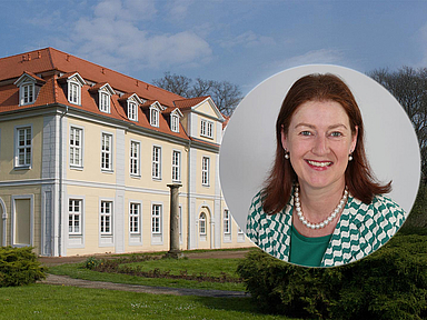 Das Foto zeigt das historische Gebäude „Friedrichsbad“ im Park des Gesundbrunnens in Hofgeismar. Die gelbe Fassade mit rotem Dach und mehreren Fensterreihen ist von einer grünen Rasenfläche umgeben. Rechts im Bild ist in einem runden Ausschnitt Pfarrerin Prof. Dr. Regina Sommer zu sehen, die ab 1. Oktober die Leitung des Evangelischen Studienseminars der EKKW übernimmt. Sie trägt eine grün-weiß gemusterte Jacke und eine Perlenkette.
