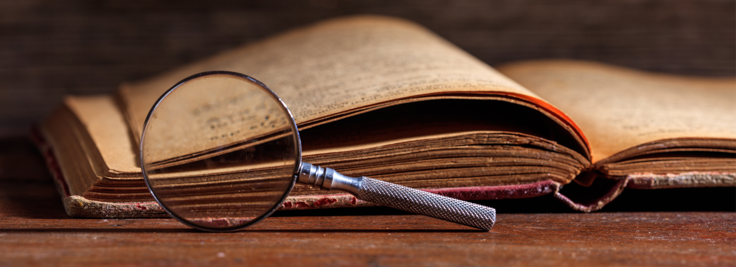 Altes Buch mit Lupe davor Altes Buch mit Lupe davor