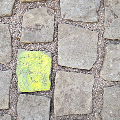 Ein gelber Straßen-Pflasterstein inmitten grauer. Foto: Peter Weidemann, pfarrbriefservice.de