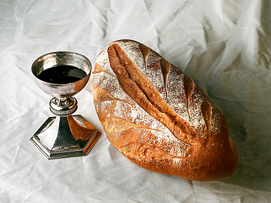 Das Foto zeigt einen gedeckten Tisch mit Brot und Wein
