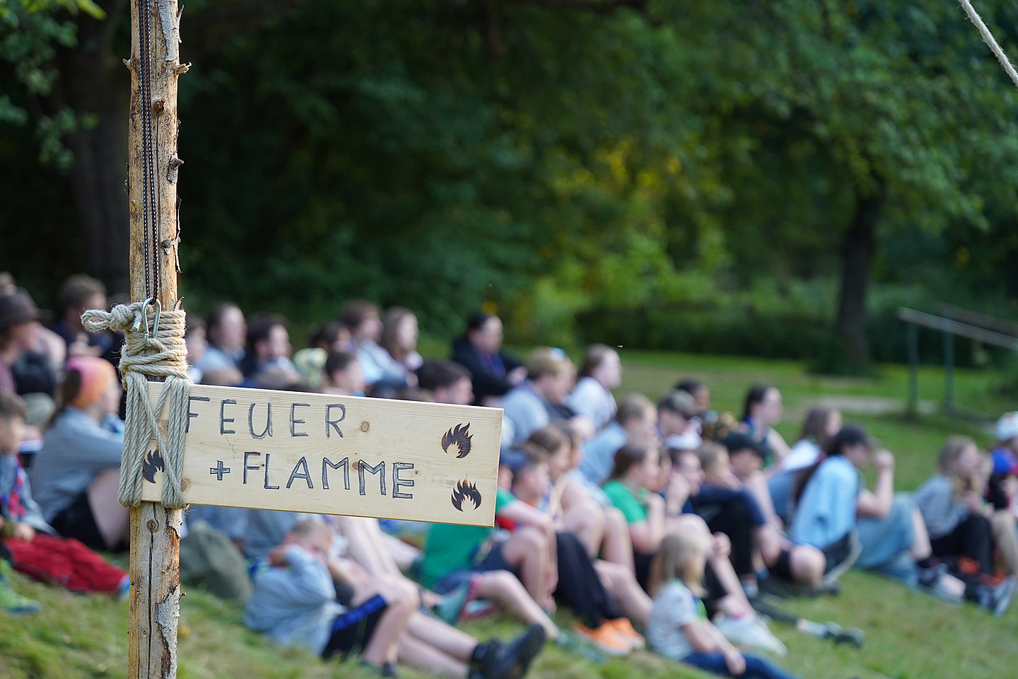 Unser Foto zeigt die jungen Menschen in der Natur. Im Vordergrund ist ein Schild mit der Aufschrift «Feuer und Flamme».