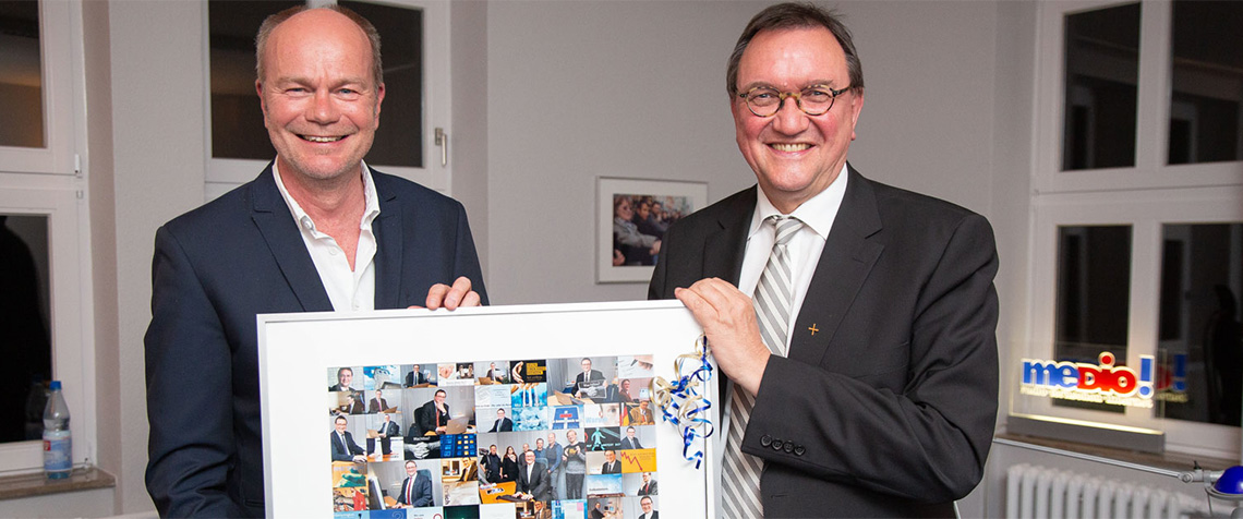 Medienhausleiter Pfarrer Christian Fischer (l.) überreichte Bischof Hein eine Fotocollage mit Motiven aus 39 Chats, verbunden mit dem Dank für «39 bewegende, bisweilen aufregende, immer aber unterhaltsame Online-Gespräche». (Foto: medio.tv/Schauderna)