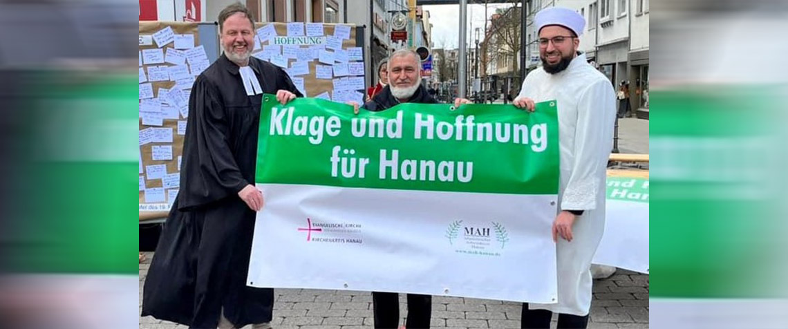 v.l.: Dekan Dr. Martin Lückhoff, Behud Yilmaz und Imam Mustafa Macit Bozkurt (Islamischer Verein Hanau) mit einem Plakat zur Aktion in Hanau. Im Hintergrund ist eine der Stellwände zu sehen, an die Zettel mit Klagen und Hoffnungen geheftet werden konnten. (Foto: Kirchenkreis Hanau) 