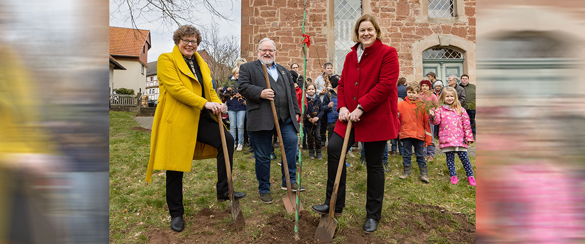 Von links: Bischöfin Dr. Beate Hofmann, Lorenz Faßhauer, Vorsitzender der Waldinteressentenschaft, Vizepräsidentin Dr. Katharina Apel pflanzten den ersten Baum vor der Dorfkirche Hilgershausen. Im Hintergrund freuen sich die Krippenspielkinder aus Hilgershausen. (Foto: medio.tv/schauderna)