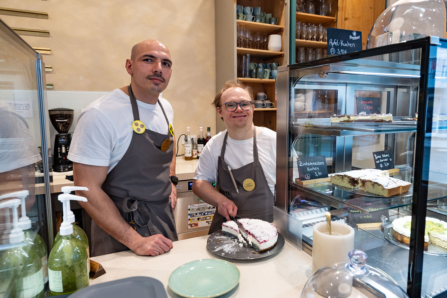 Pädagoge Niko Rizidis und Servicekraft Lukas Haupt an der Theke