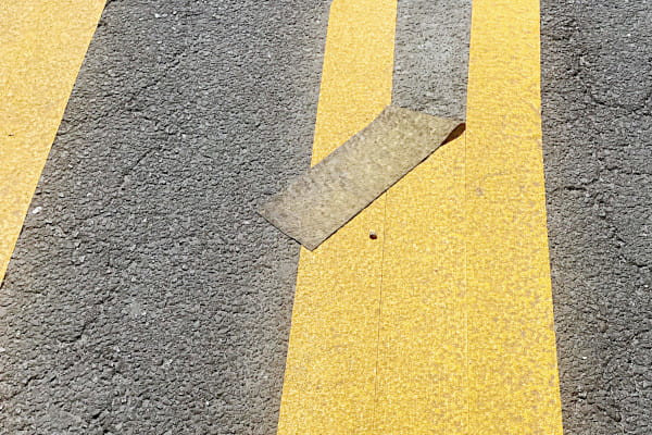 Ein gelber Zebrasteifen mit einem Stück abgelösten Streifens (die Lücke). Ein gelber Zebrasteifen mit einem Stück abgelösten Streifens (die Lücke). Foto (Ausschnitt): Günter Beck, pfarrbriefservice.de