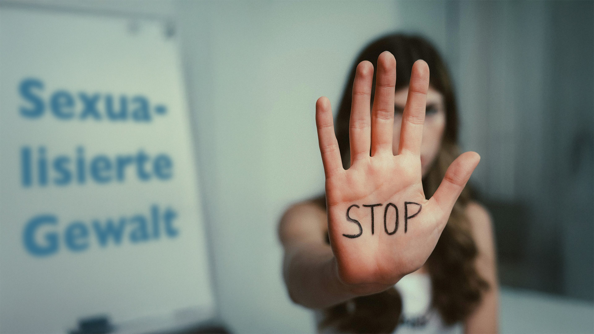 Eine Frau zeigt ihre Hand, auf der Stop geschrieben ist. Daneben steht der Schriftzug "Sexualisierte Gewalt".